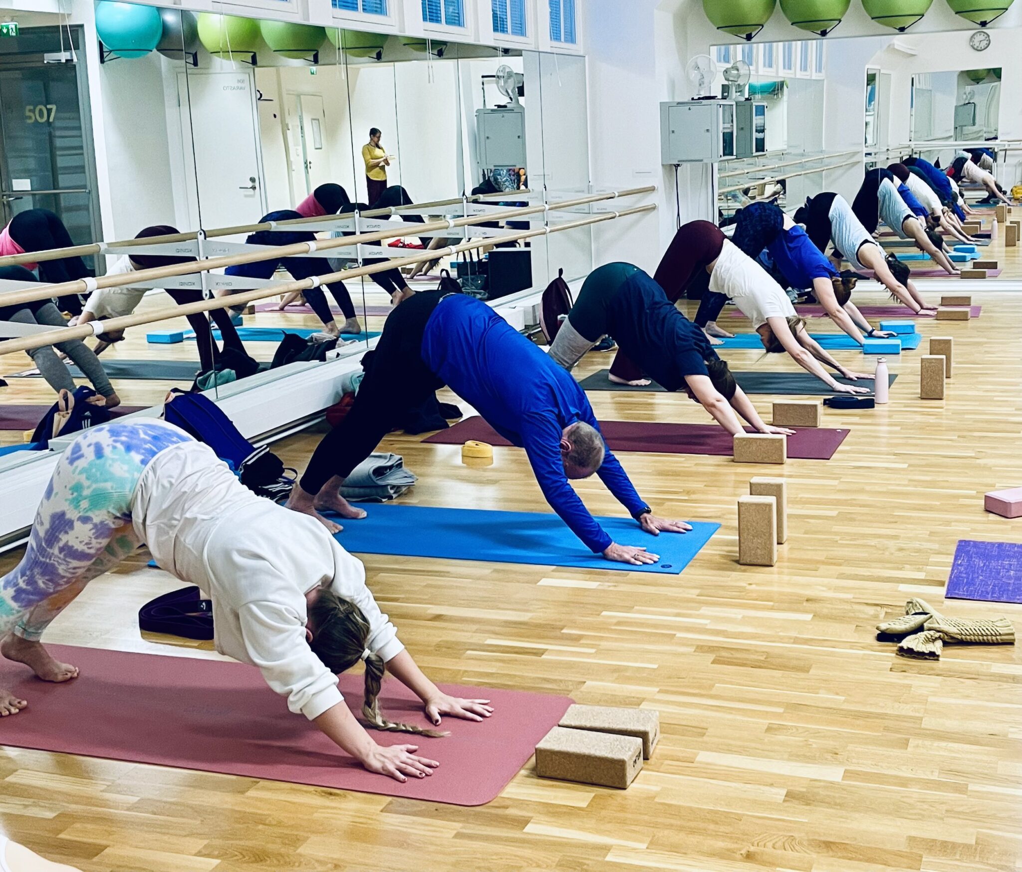 Joogakoulutus Helsingissä, oppilaita tekemässä alaspäin katsova koira -asanaa.